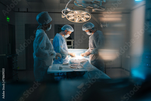 Remote portrait of diverse cooperating team of doctors, surgeons and African-American nurse processing surgical operation in operating room modern hospital emergency department. Concept of surgery.