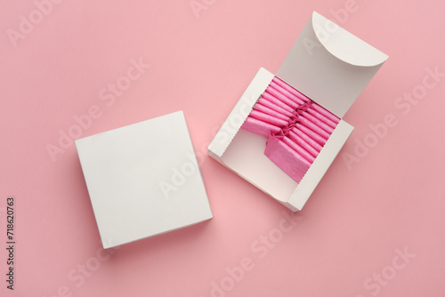 Box with sanitary pads on pink background. Feminine hygiene photo