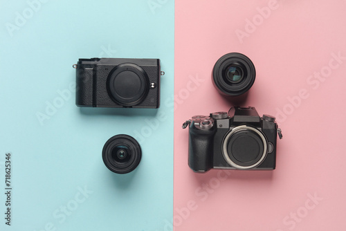 Two modern mirrorless cameras with a lens on a blue pink background. Top view