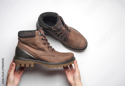 Hands holding a winter leather boot on a white background