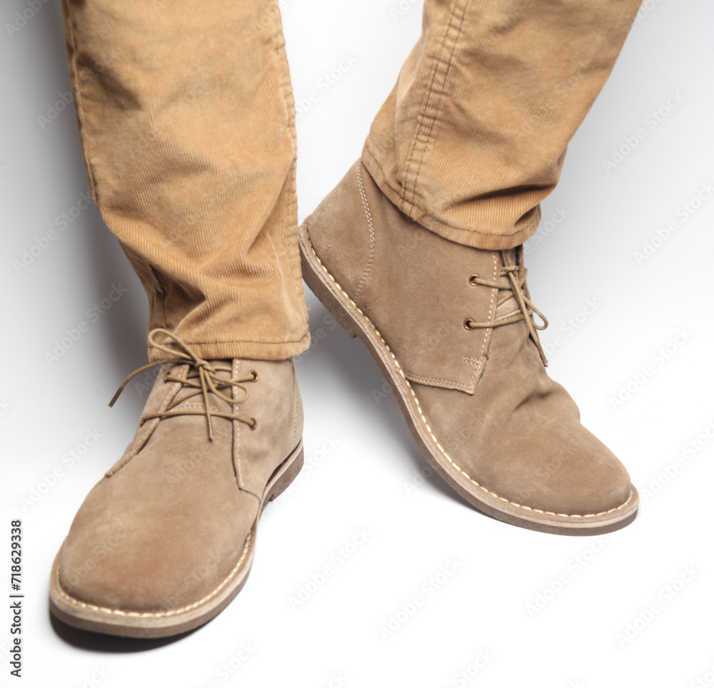 Male legs in beige pants and suede desert shoes on a white background Male legs in beige pants and suede desert shoes on a white background