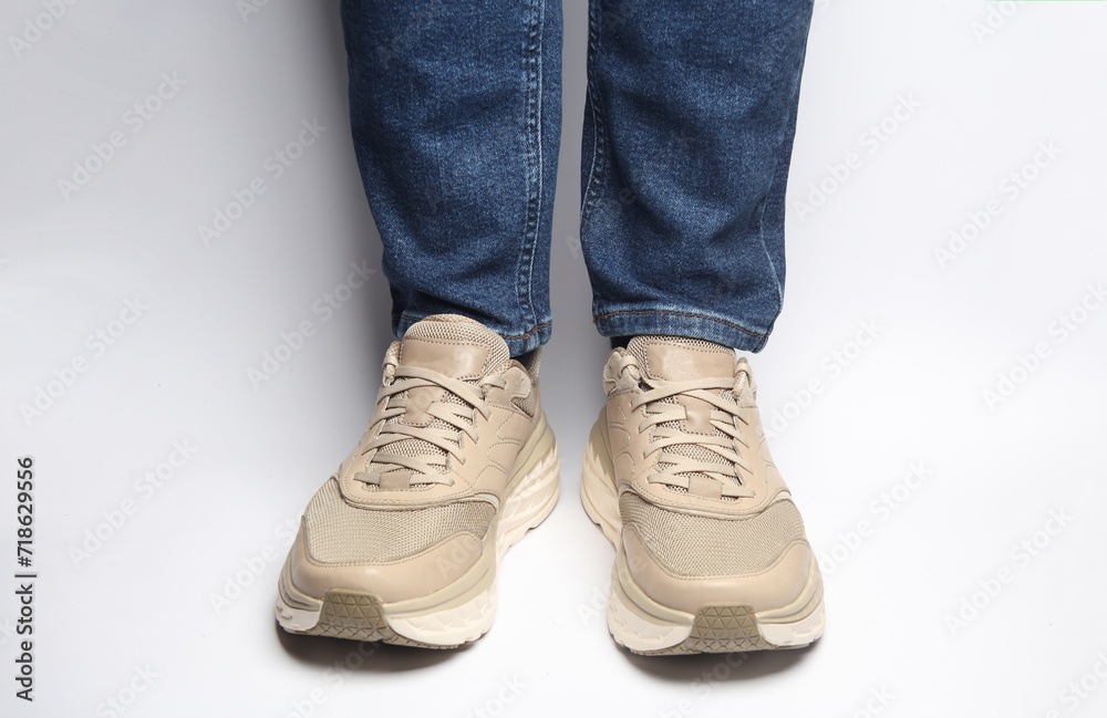 Male legs in jeans and sneakers on a white background Male legs in jeans and sneakers on a white background