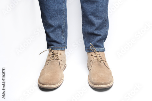 Male legs in jeans and desert shoes on a white background