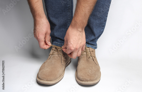Man tying laces of suede shoes on white background © splitov27
