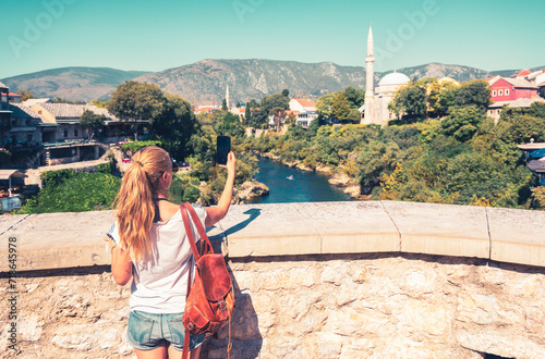 Woman tourist taking photography of famous old bridge in Mostar- Travel, tourism in Bosnia