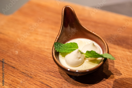 Artistic custard dessert with mint garnish in a soup spoon, Chefs Table
