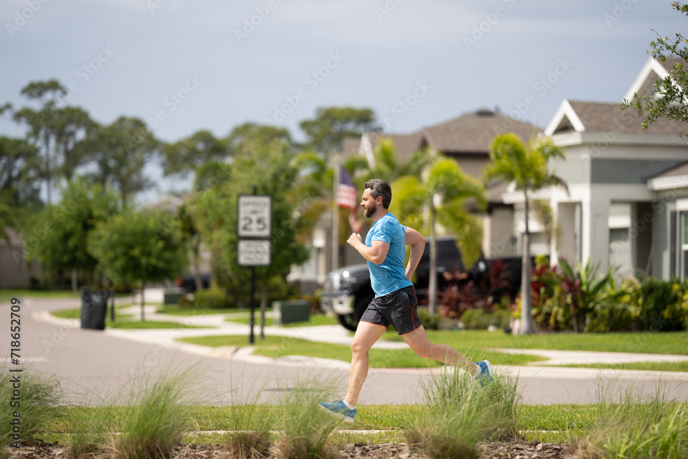 Running man sprinting workout outdoor. Fit athlete man running on american neighborhood. Sporty fit caucasian male, fitness sport model working out outside in full length.