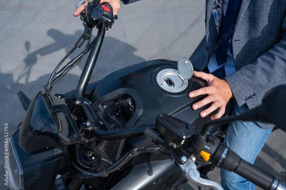 A man opened the charging socket on an electric motorcycle. A man opened the charging socket on an electric motorcycle.