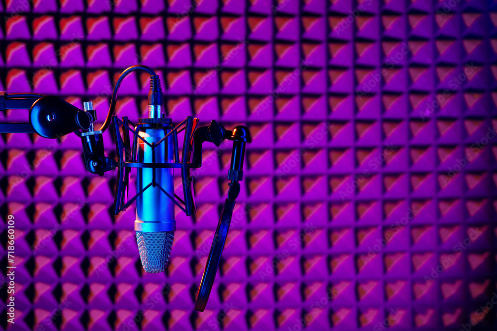 Professional studio microphone against acoustic foam panel background in neon light