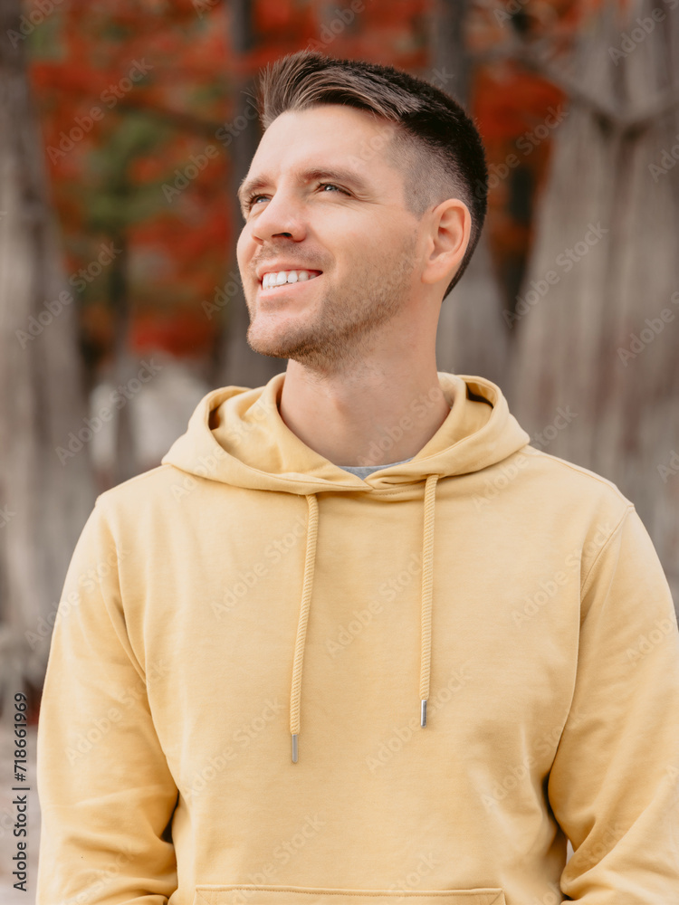 Obraz premium Handsome man in autumnal park. Portrait of smiling caucasian man in yellow hoodies