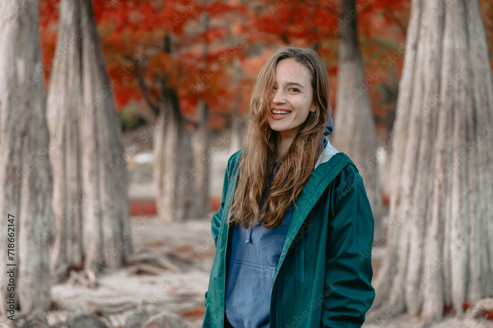 Cheerful woman walking down the park and looking at the camera. People in autumnal forest. Cheerful woman walking down the park and looking at the camera. People in autumnal forest.