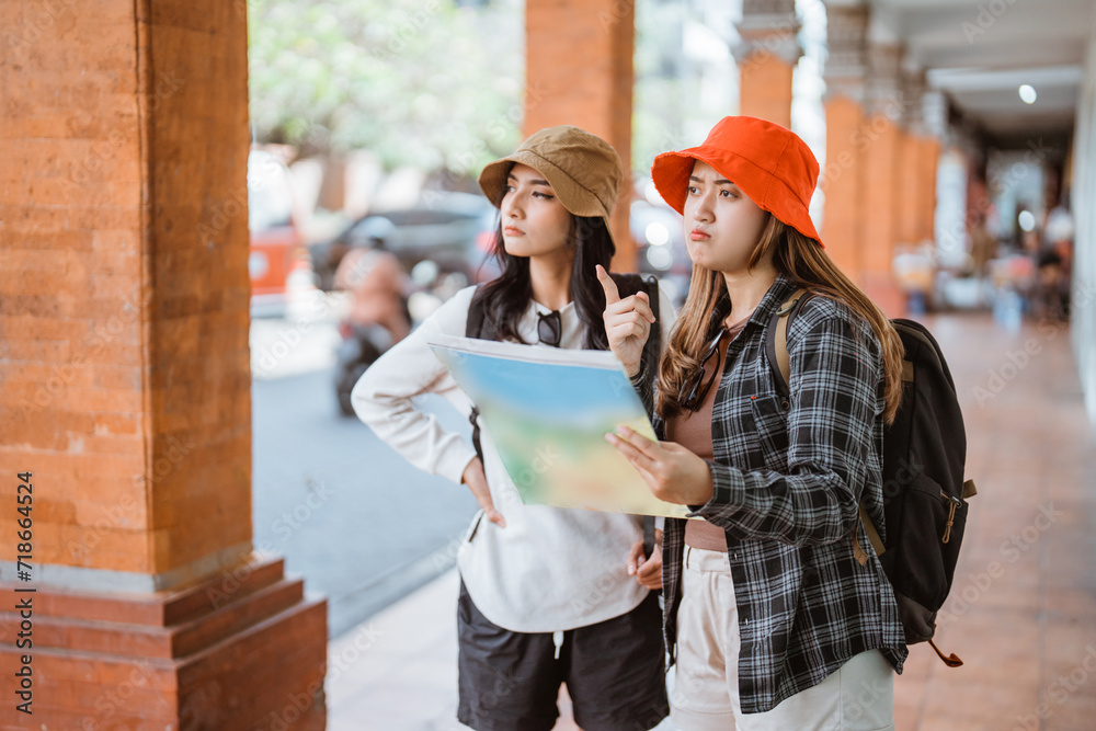 two Asian tourists look at a map on their way to a tourist destination two Asian tourists look at a map on their way to a tourist destination