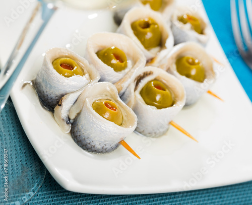 Delicious rolls of salted herring with pickled olives stuffed with bell pepper.. photo