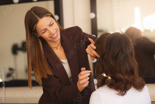Barber and beauty hairstyle concept. Young female hairdresser fixing hair of girl with hairspray wax