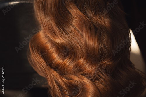 Detailed view of shiny auburn hair highlighting its natural waves and texture background