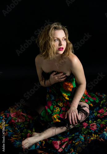 beautiful naked blonde girl with red lips in different colored Ukrainian traditional scarf on a black background