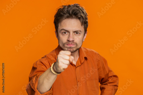 Quarrel. Displeased aggressive unhappy Caucasian man gesturing hands with irritation and displeasure, blaming scolding for failure, asking why this happened. Bearded guy isolated on orange background