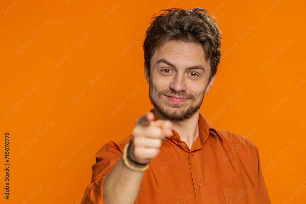 I choose you. Caucasian smiling man pointing finger to camera and looking with playful happy expression making winner choice showing direction. Handsome young guy isolated on orange studio background I choose you. Caucasian smiling man pointing finger to camera and looking with playful happy expression making winner choice showing direction. Handsome young guy isolated on orange studio background