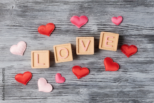 Romantic Love Message with Red and Pink Hearts and wooden blocks on Wooden Background
