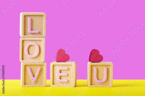 Wooden Blocks Spelling ‘LOVE U’ with Hearts on Yellow Background