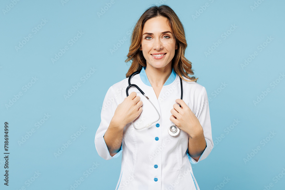 Female smiling happy doctor woman wears white medical gown suit work in hospital clinic office hold stethoscope looking camera isolated on plain blue background studio. Health care medicine concept. Female smiling happy doctor woman wears white medical gown suit work in hospital clinic office hold stethoscope looking camera isolated on plain blue background studio. Health care medicine concept.