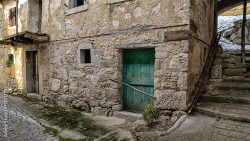 Fototapeta Naklejka Na Ścianę i Meble -  Ruins of traditional rural house facing on an alley of an almost abandoned Italian mountain village. Canalaz, Grimacco, Udine province, Friuli Venezia Giulia, Italy. Urbex photography.