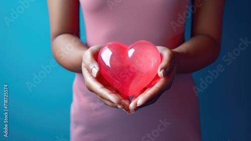 Close-up of a woman's hands holding a pink heart. Valentine's Day greeting card. A symbol of love.