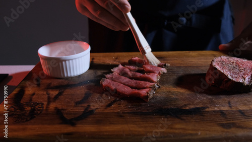 the cook greases the pieces of sliced meat with olive oil before serving. photo