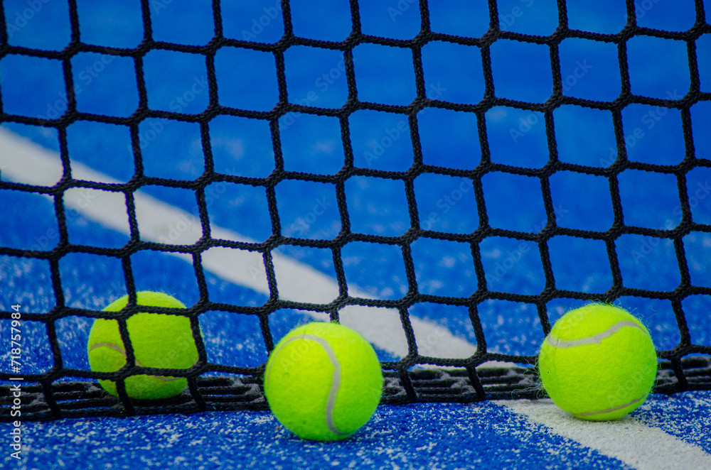 Three balls in a blue paddle tennis court, racquet sports concept