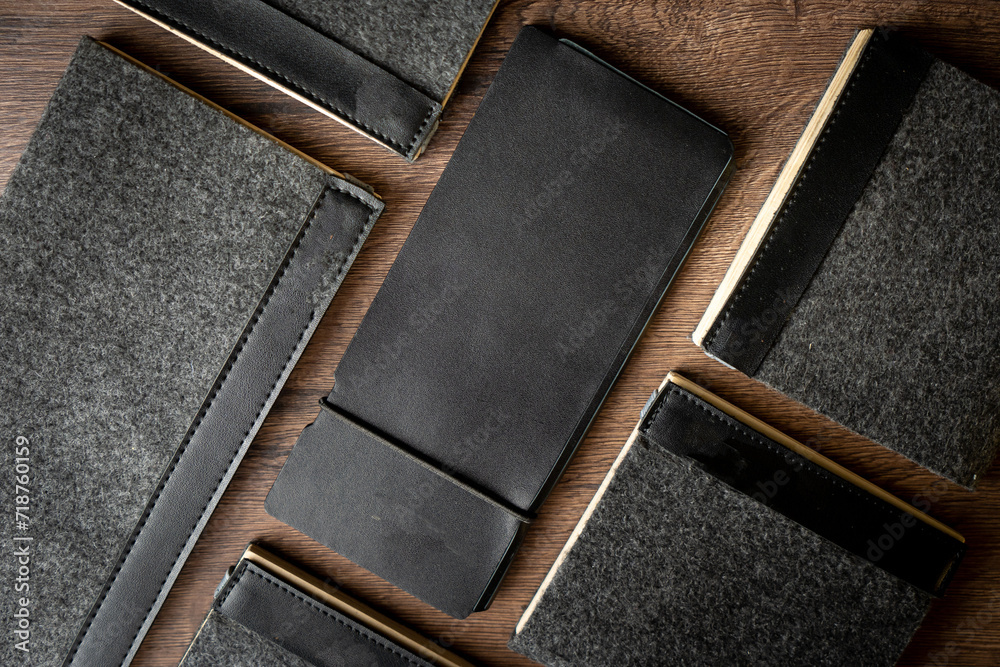 Fototapeta premium Handmade black wallet made of genuine leather on a wooden background. Close-up, top view.