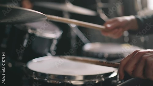 Drummer plays drums in music studio at band rehearsal, close up with selective focus.