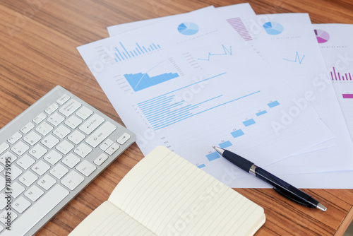 Close up of male freelance worker hand working on laptop and pointing with finger on analysis data with business graph and chart of information diagram on office desk in the morning