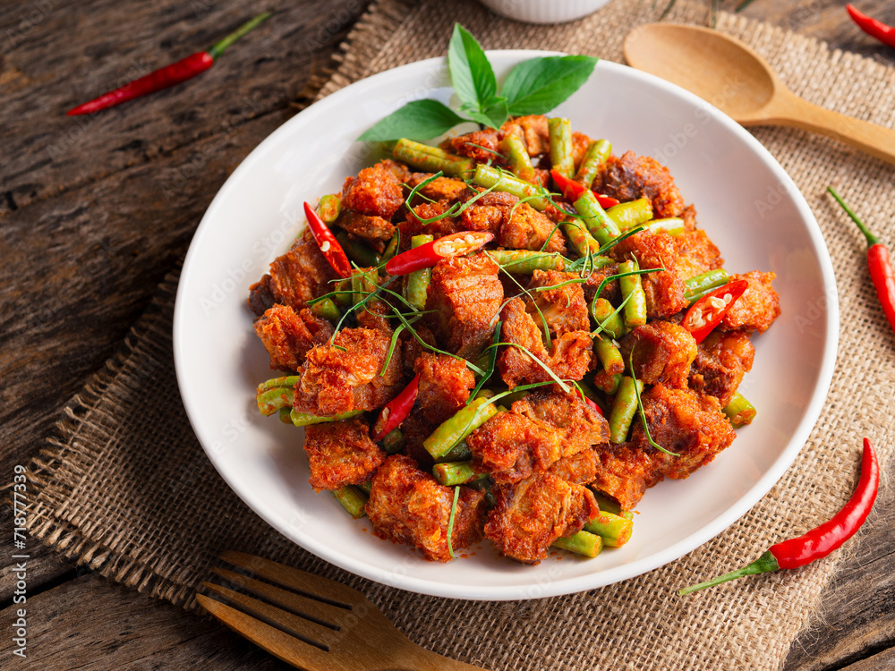 Stir fried crispy pork with red curry in white plate on wooden table background. Thai Food Stir fried crispy pork with red curry in white plate on wooden table background. Thai Food