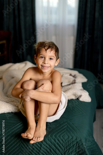 Cute child  boy  sitting at home in bed after shower