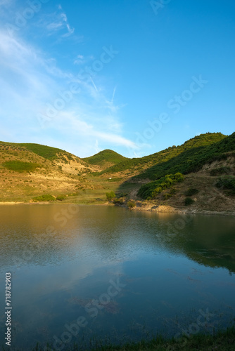 Beautiful lakeside view from a small lake in Albania  with lush green trees  blue sky and sunlight