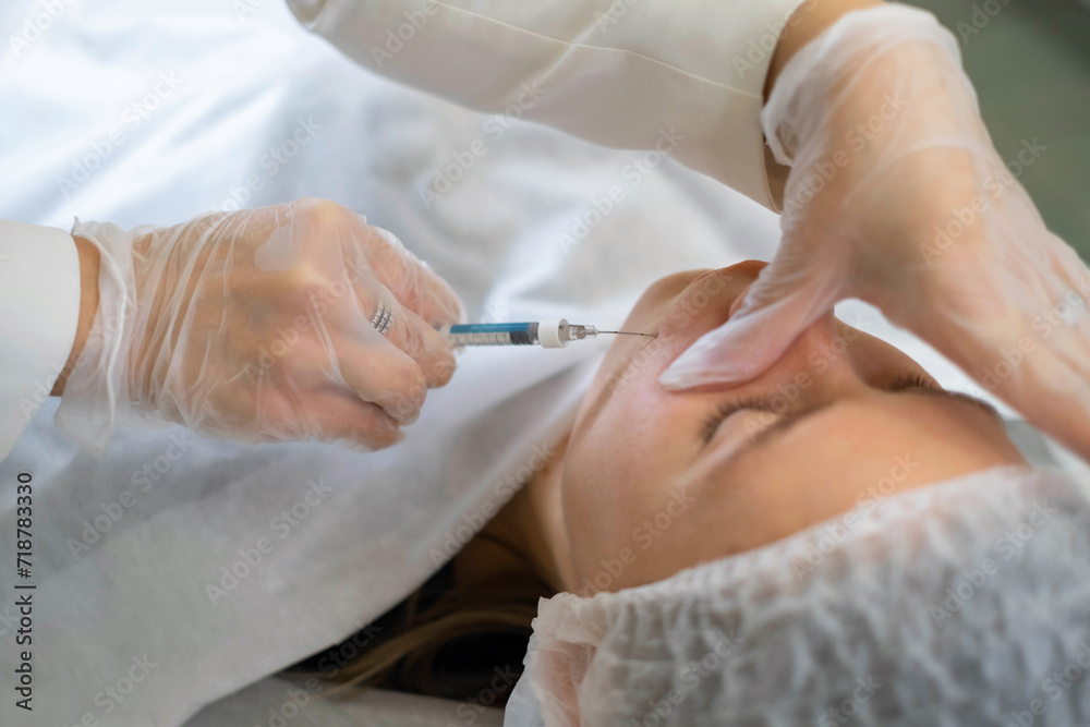 Cosmetologist administers an injection into the nasolabial fold, targeting signs of aging. Precision in cosmetic treatments is key. Cosmetologist administers an injection into the nasolabial fold, targeting signs of aging. Precision in cosmetic treatments is key.