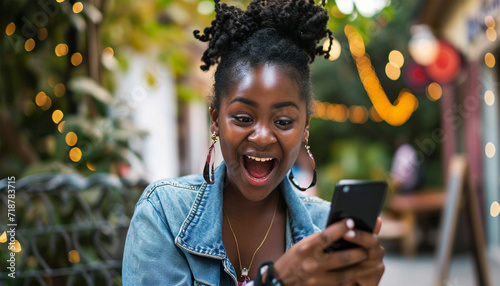 Excited African American woman using phone. Black woman, phone and fist celebration in studio, blue yellow background and winning online prize. Happy female model celebrate mobile promotion, bonus 