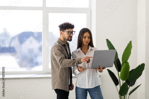 Two colleagues discussing work on a laptop in office