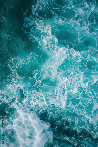 Vertical From above aerial view of turquoise ocean water with splashes and foam for abstract natural background and texture.