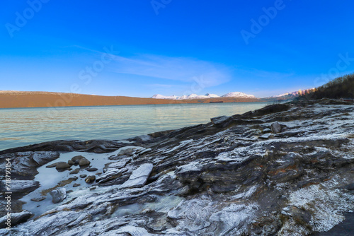 beautiful panorama with frozen ground and mountains in the background
