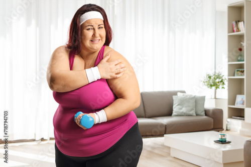 Plus size woman exercising and holding her painful shoulder