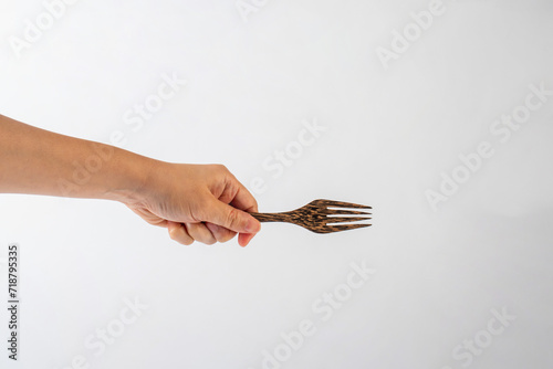 Hand and wooden fork on white background. © apinya