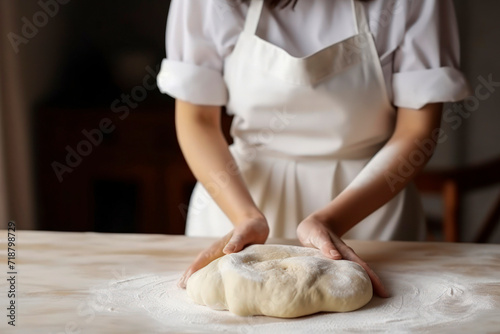 Beautiful and strong women's hands baker chef knead the dough on the wooden table make for bread, pasta or pizza. Lifestyle concept suitable for meals and breakfast. Close-up.