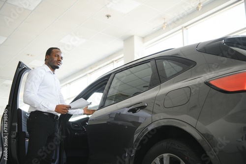 young african american car dealership principal standing in vehicle showroom © Serhii