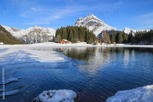 Winter landscape of the frozen Arni Lake with the snow-convered Alps peak Windgaellen at the background photo