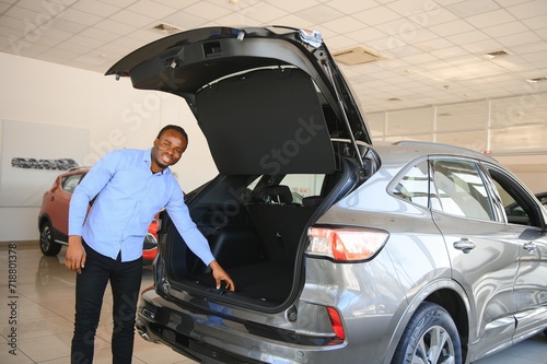 His dream car. Happy young African man looking excited choosing a car at the dealership