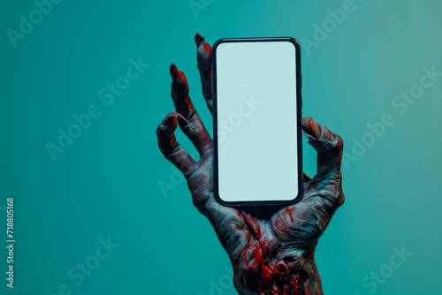 Creepy halloween monster zombie hand holding a mobile phone with a blank screen photo