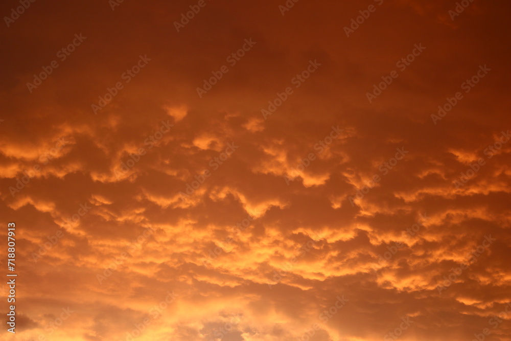 Bright orange cumulus clouds in the sky during a fiery sunset
