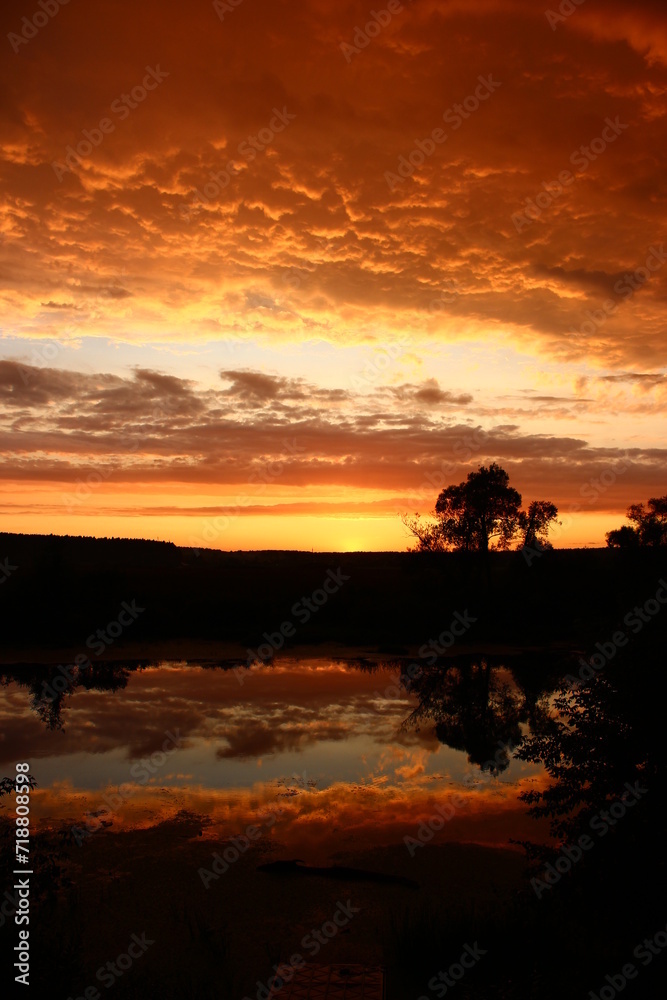Colorful fiery sunset with a cloudy sky over the river, clouds painted in rich colors