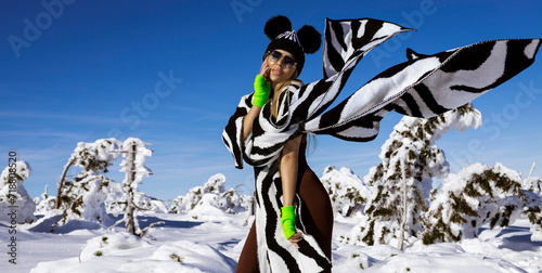 Beautiful woman wearing winter fashionable jacket and winter boots and is posing in the mountains.